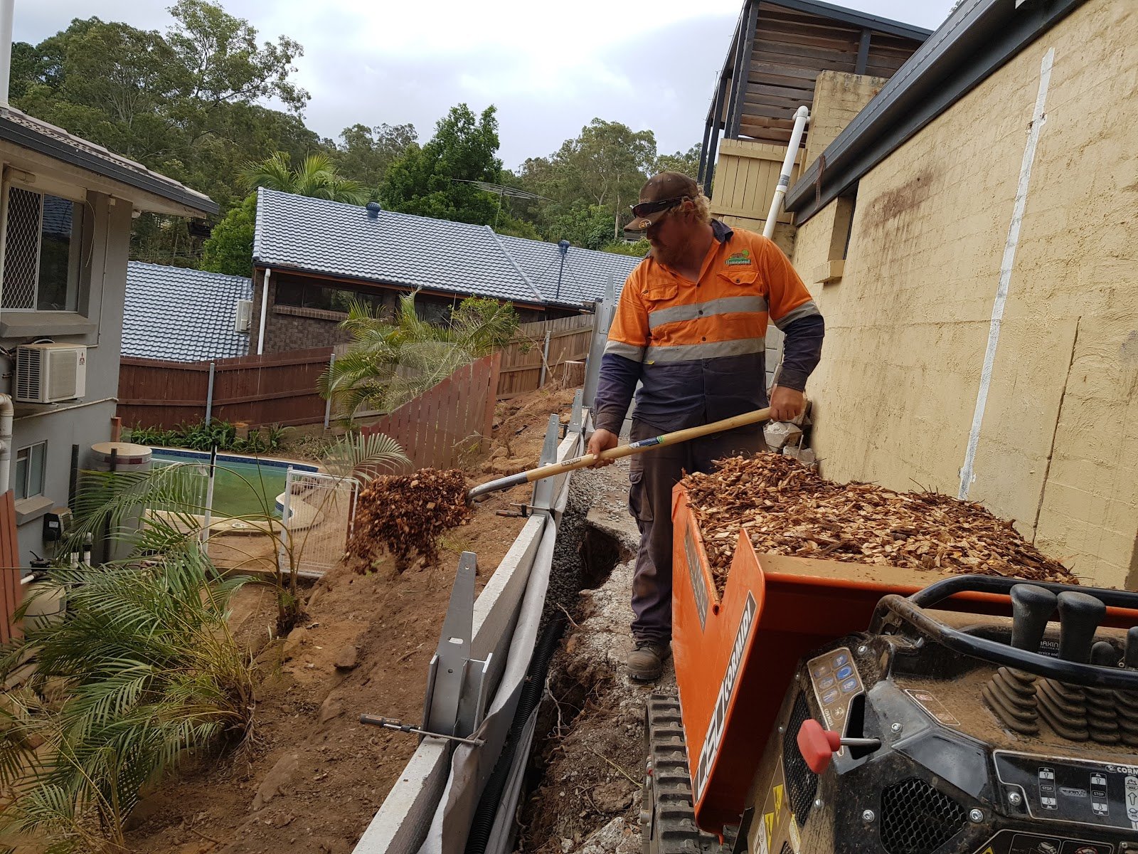 A trader is loading leaves from a mini dumper using shovel