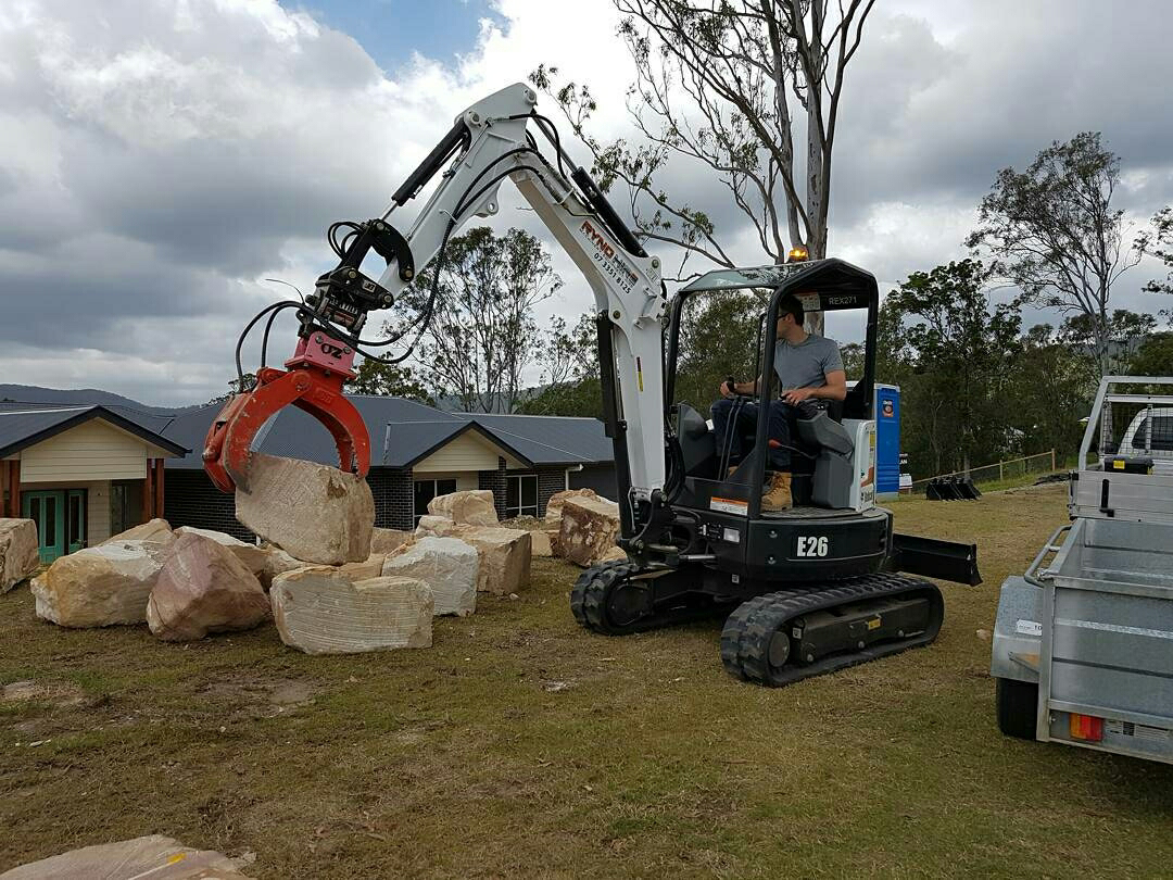 2,7tn excavator with grab A man is operating an excavator with hydraulic rock grab attachment