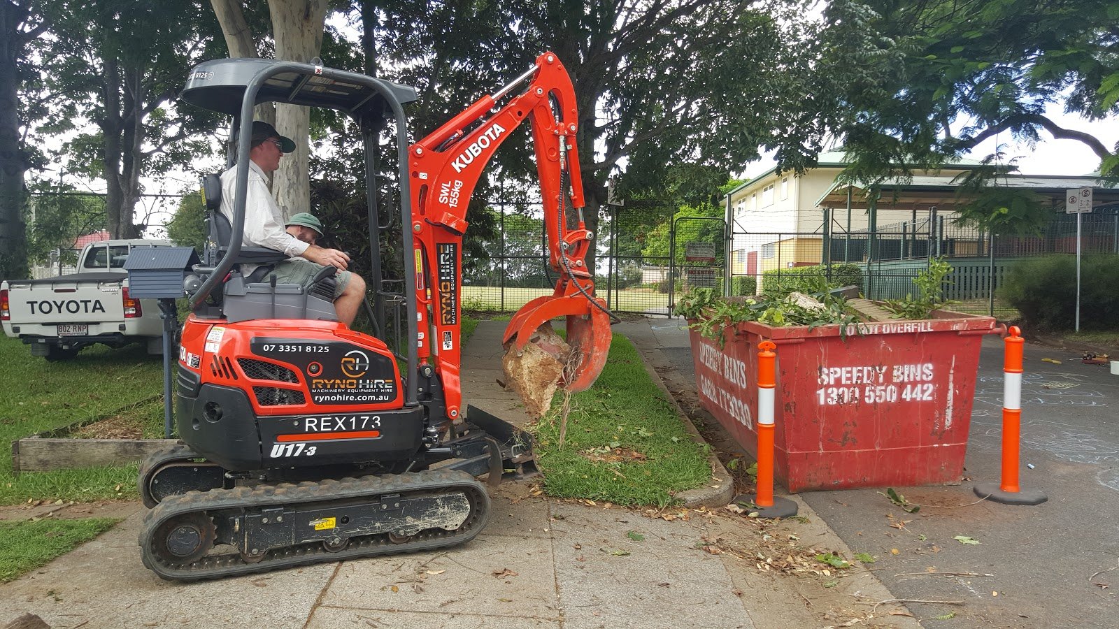Excavator Grab A man is operating an excavator with hydraulic rock grab attachment to the bin area